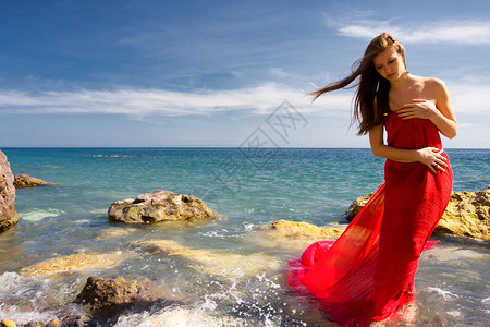 海边沙滩上穿红裙子的美女图片
