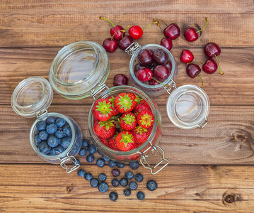 罐头蓝莓草莓和木制桌上樱桃中的新图片