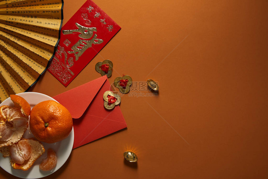 盘子上的橘子象形文字粉丝金饰品和棕色背景的红包图片