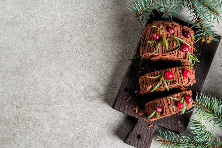 传统的圣诞甜点圣诞原木蛋糕巧克力奶油蔓越莓和迷迭香树枝图片