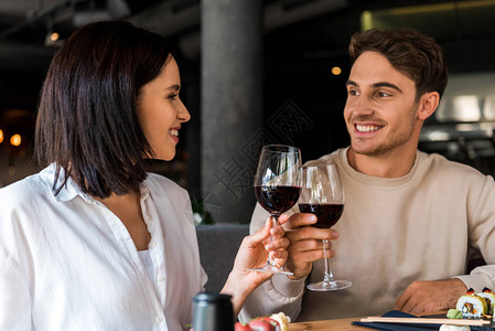 快乐的男人和快乐的女人在寿司附近的红酒与图片