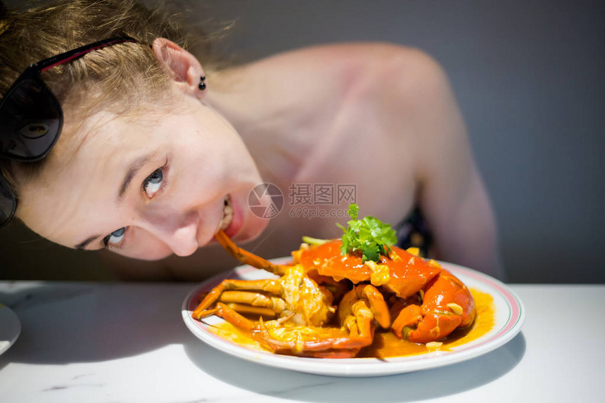 年轻的游客吃新加坡风格的热辣椒蟹图片