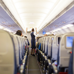 乘客坐在座位上的飞机和身着制服的空姐在过道旅游高清图片素材