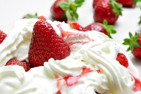 一碗开胃草莓和奶油的特写图片