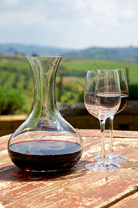 红酒瓶中的红酒和葡萄园中的两个酒杯图片