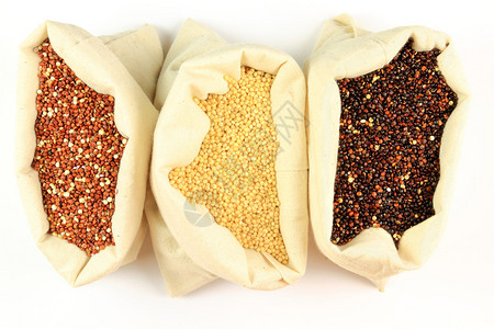 红色白色和黑色有机藜麦种子从白色背景的白色织物袋装图片