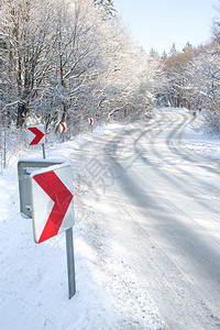 带有红色方向箭头的弯曲冬季道路图片