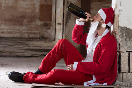 酗酒的圣诞老人喝一瓶酒图片