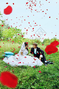 新婚夫妇在落下的玫瑰花瓣下草坪上的图片