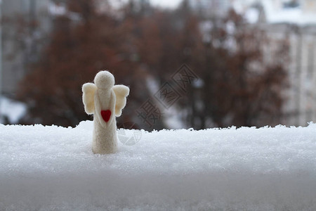 一个羊毛玩具天使站在雪地上站在阳台对街的栏图片