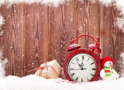 圣诞礼物盒雪人玩具和雪中的闹钟使用图片