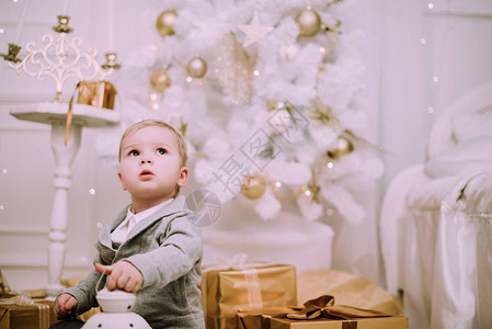 快乐的小男孩在圣诞树附近玩金子图片