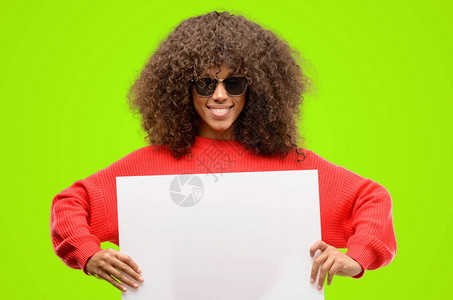 戴墨镜的非洲裔美国女手持空白广告横幅广告报价或公告的好海报图片