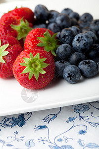 白盘子上的新鲜草莓和蓝莓图片