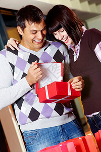 快乐的女孩和英俊的男人寻找着开的红礼物图片