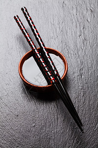 黑石背景酱油碗上的日本寿司筷子图片