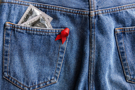 蓝色牛仔裤口袋里的红丝带和银色避孕套有助于提高认识图片