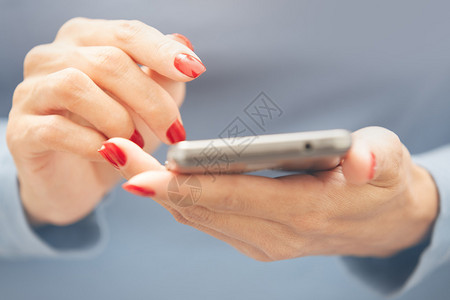 使用智能手机修红指甲的女背景图片