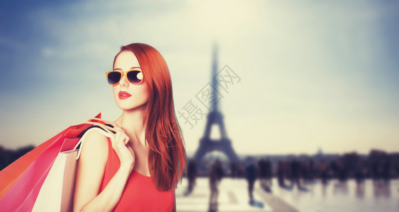 巴黎背景下提着购物袋的红发女郎背景图片