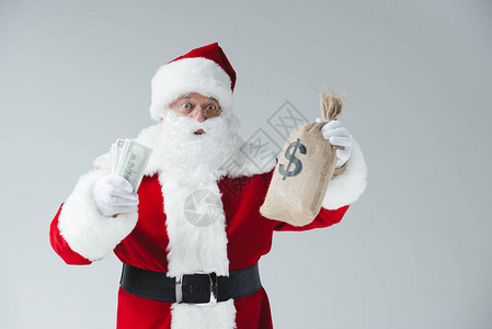 惊讶的圣诞老人拿着美元钞票和被白图片