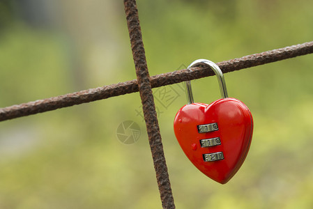 红锁以心脏的形状固定在一块生锈的混凝背景图片