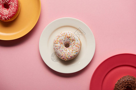粉红色背景盘子上甜圈的顶部视图图片