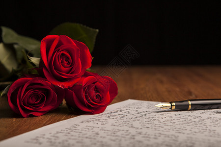 钢笔纸和鲜花玫瑰的静物特写图片