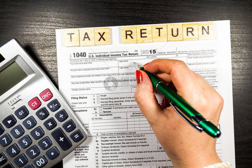 计算器和女手工填写美国个人所得税申报表1040收入和税收概念图片