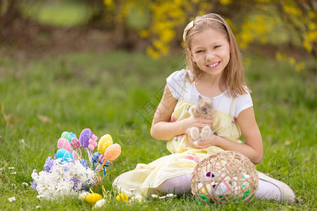 美丽的微笑的小女孩抱着可爱的兔子图片