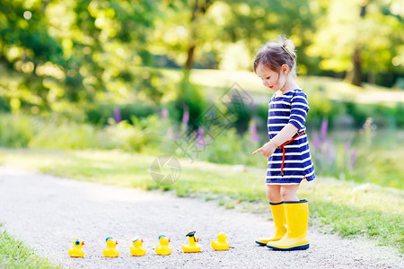 2岁的可爱小孩在夏日公园玩黄色橡皮鸭图片