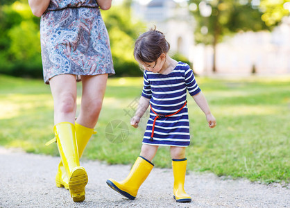 母亲和幼儿小女孩穿着黄色橡皮靴图片