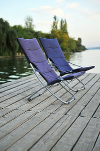 两张蓝色折叠椅在河上图片