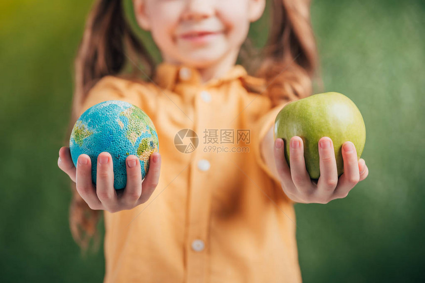 儿童在模糊背景上持有全球模型和苹果的选择焦点图片