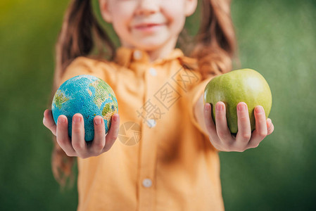 4月22地球日儿童在模糊背景上持有全球模型和苹果的选择焦点背景