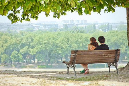 情爱的情侣坐在公园长椅上享受风图片