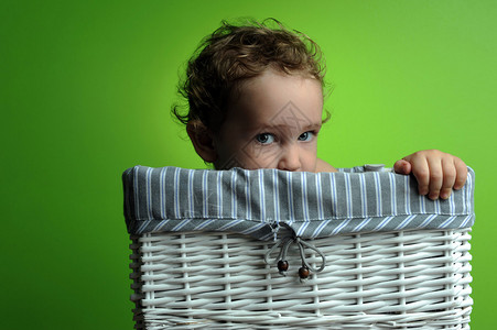 婴儿坐在篮子里越过绿色背景墙背景图片