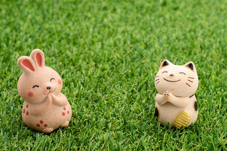 日本幸运猫和快乐的兔子在草地上祷告背景图片