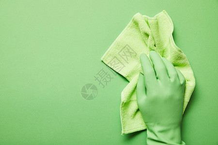 持有绿色抹布的橡胶手套中的背景图片