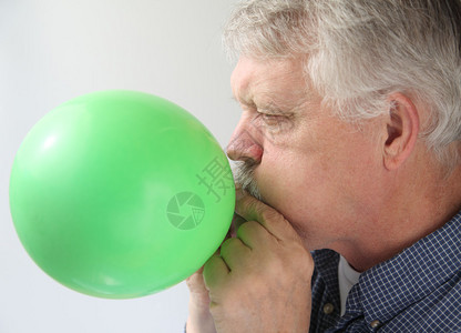 一个人吹了一个绿色的气球背景图片