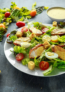 新鲜健康的凯撒沙拉配鸡肉鸡蛋鹌鹑西红柿奶酪和面包丁图片
