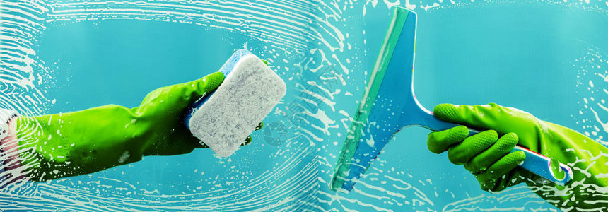 手套上的橡胶刮刀可清洁涂过肥皂的窗户并清除蓝色背景的条纹图片