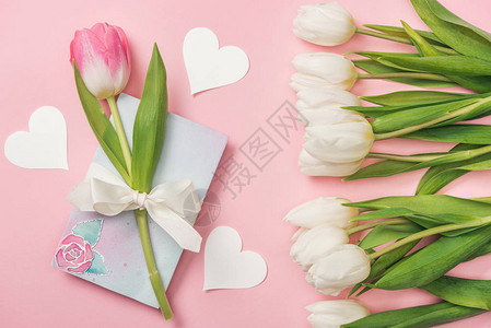 粉红色郁金香在贺卡纸心和粉红色背景图片