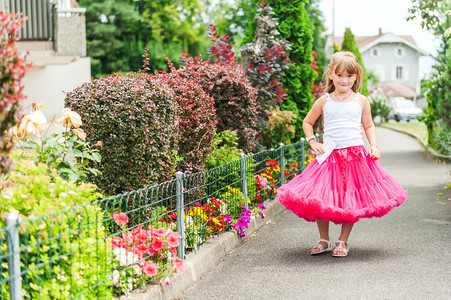 美丽的小女孩穿着明亮的粉红色裙和白色上衣图片