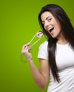 女人拿着寿司片和筷子在绿图片