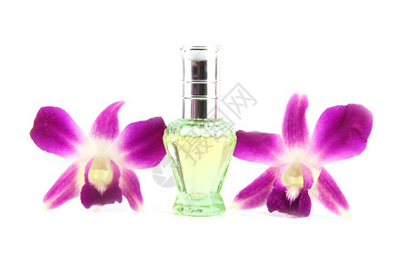 白色背景上的紫色兰花和绿色香水瓶图片