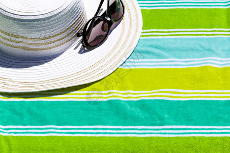 沙滩巾上戴着太阳镜的夏天帽子图片