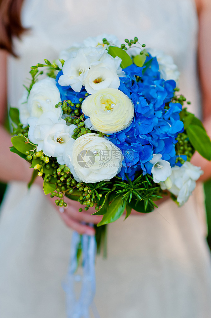 新娘拿着一束蓝色绣球花的婚礼花束图片