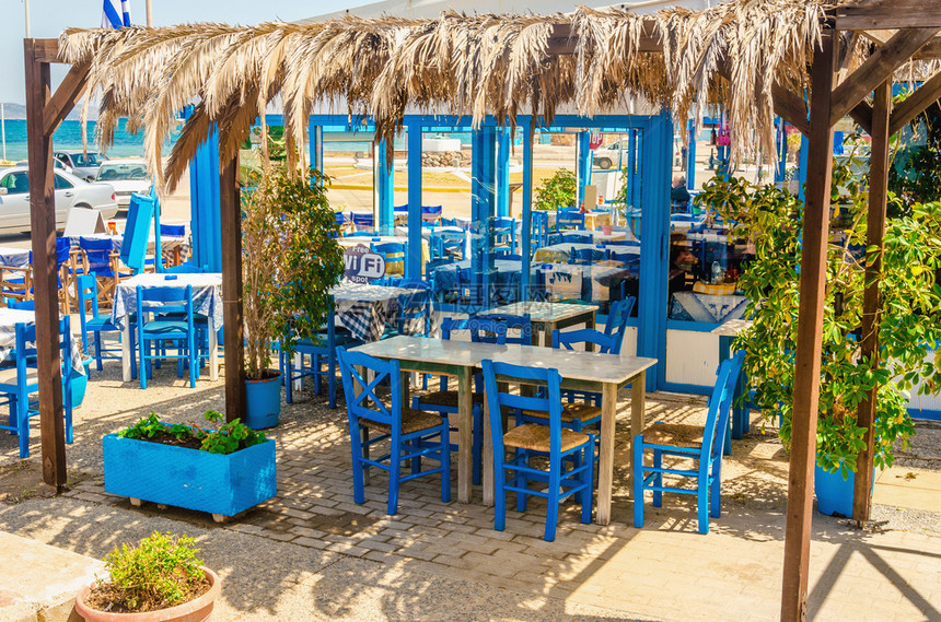 希腊科斯海滨滩上一家希腊餐馆棕榈叶皮的Pergola下蓝图片