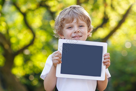 拥有平板电脑户外用品的可爱快乐的小孩图片