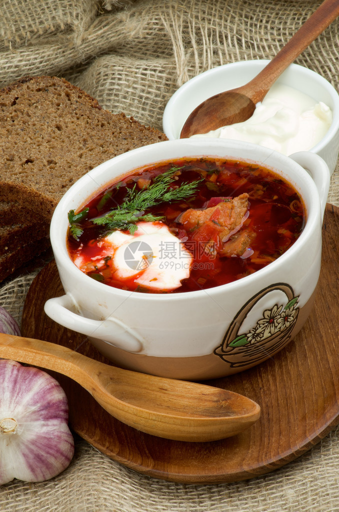 乌克兰全国传统汤用甜菜蔬菜和肉用木勺在木盘上安排红面包大蒜和酸图片